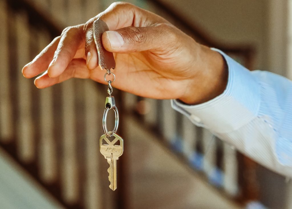 Black male hand holding key - representing leasing an apartment 