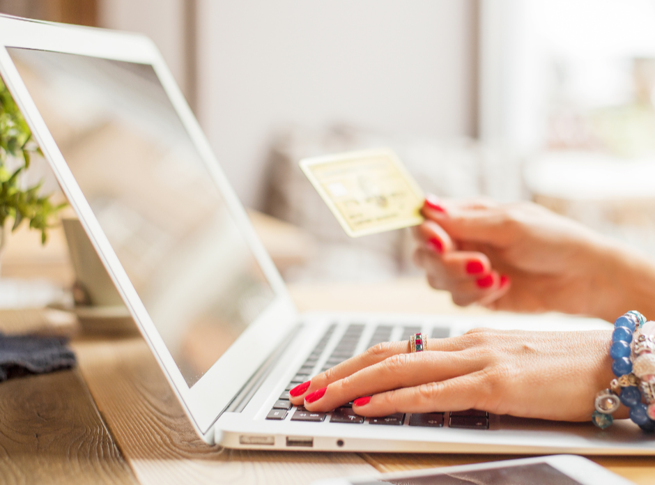 woman holding credit card shopping online via laptop