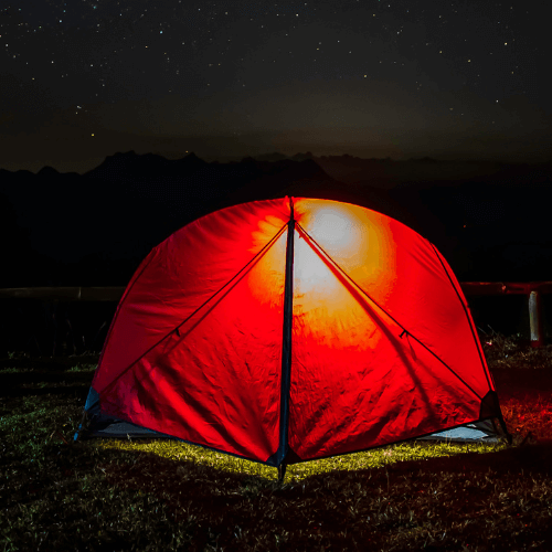 Tent at night glowing orange from light inside